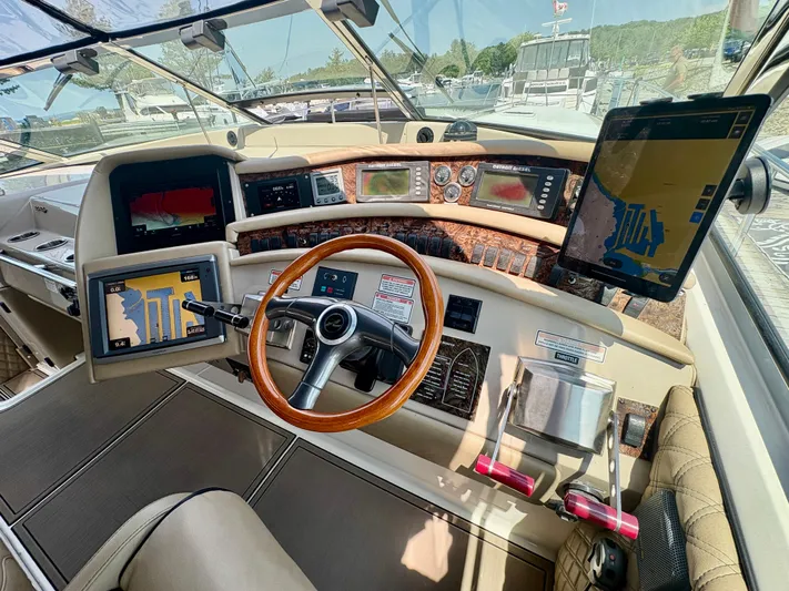 Top Gunns Yacht Photos Pics Cockpit of 1998 Sea Ray 500 Sundancer with navigation screens and wooden steering wheel.