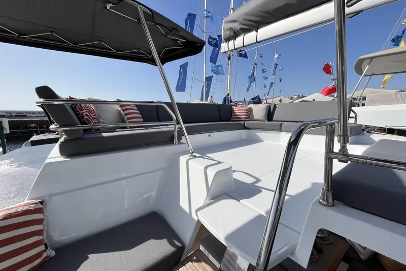  Yacht Photos Pics 2023 Fountaine Pajot Tanna 47 yacht deck with cushioned seating and nautical flags.