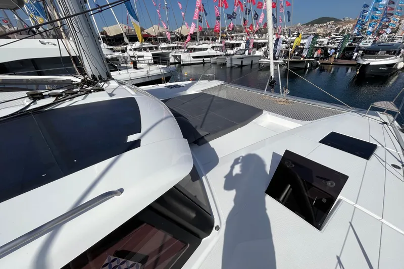  Yacht Photos Pics 2023 Fountaine Pajot Tanna 47 catamaran at marina, surrounded by boats and colorful flags.