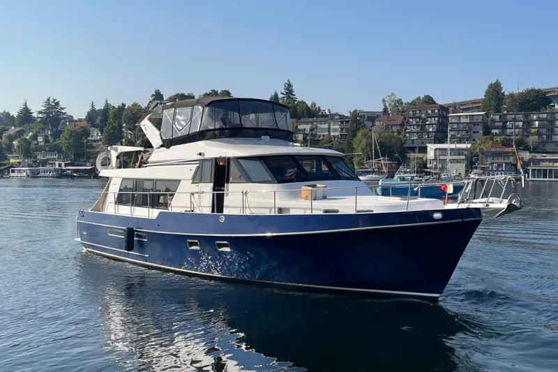 The Dude Yacht Photos Pics 1995 Ocean Alexander 486 yacht cruising on a calm waterway, surrounded by scenic waterfront homes.