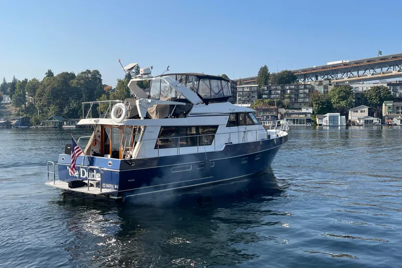 The Dude Yacht Photos Pics 1995 Ocean Alexander 486 yacht on calm water, with cityscape and bridge in the background.