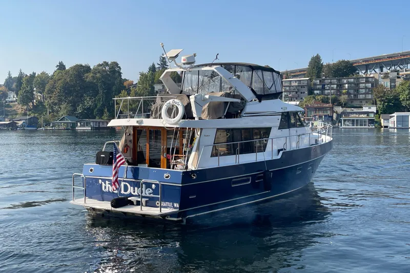 The Dude Yacht Photos Pics 1995 Ocean Alexander 486 yacht on water, with American flag, near shoreline and buildings.