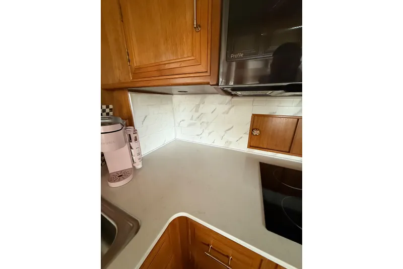 The Dude Yacht Photos Pics 1995 Ocean Alexander 486 yacht kitchen with wooden cabinets and modern appliances.