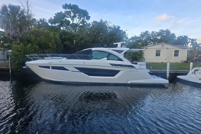  Yacht Photos Pics 2018 Cruisers Yachts 50 Cantius docked on a calm waterway, surrounded by trees.