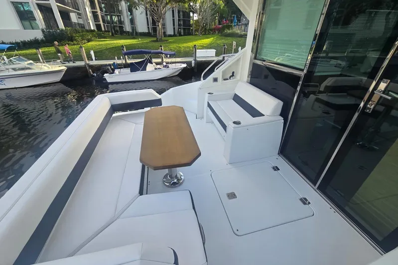  Yacht Photos Pics 2018 Cruisers Yachts 50 Cantius deck with seating and table, docked by waterfront.