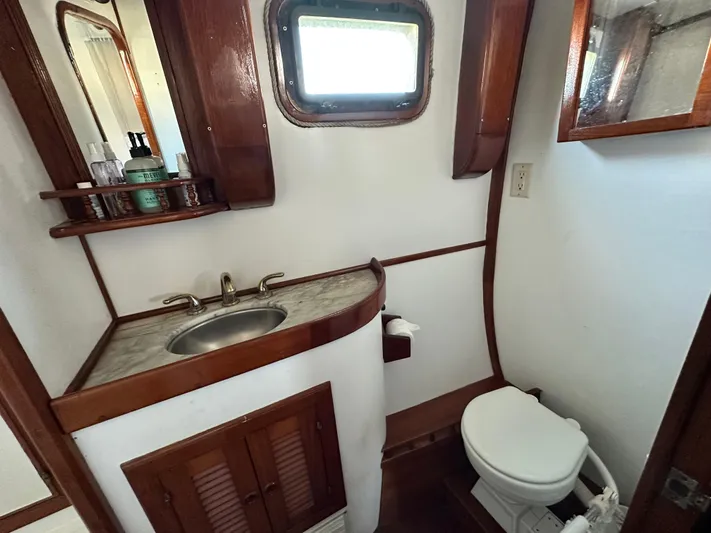 Whiskey River Yacht Photos Pics 1981 Island Trader 46 yacht bathroom with sink, toilet, wooden cabinetry, and porthole window.