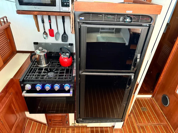 Whiskey River Yacht Photos Pics Galley kitchen in 1981 Island Trader 46 yacht with stove, fridge, and utensils.
