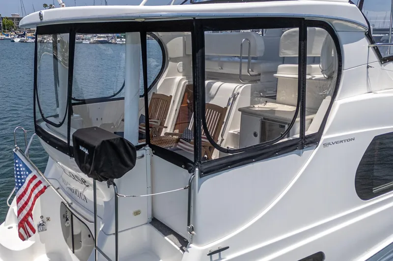 At Ease Yacht Photos Pics 2004 Silverton 39 Motor Yacht with American flag, docked in marina.