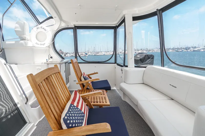At Ease Yacht Photos Pics 2004 Silverton 39 Motor Yacht interior with wooden chairs, American flag pillows, and marina view.