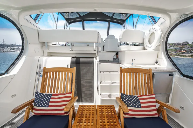 At Ease Yacht Photos Pics 2004 Silverton 39 Motor Yacht interior with wooden chairs, American flag cushions, and ocean view.