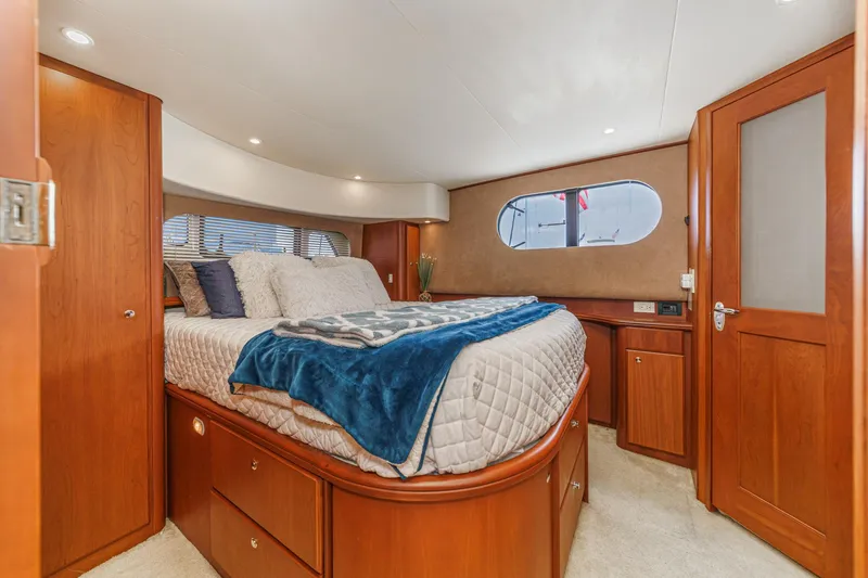 At Ease Yacht Photos Pics Luxurious cabin interior of 2004 Silverton 39 Motor Yacht with cozy bed and wooden furnishings.