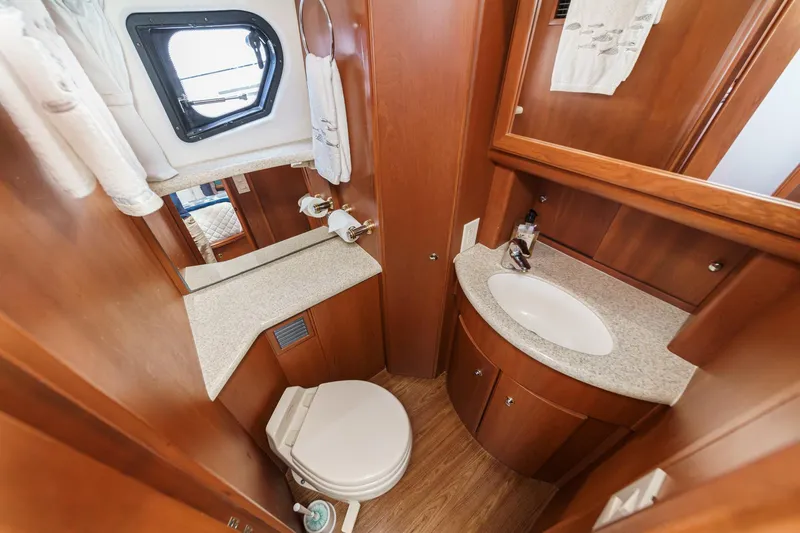 At Ease Yacht Photos Pics 2004 Silverton 39 Motor Yacht bathroom with wood cabinetry, sink, and porthole window.