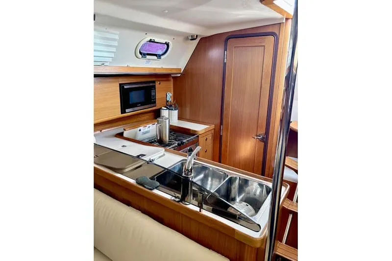 Falken Yacht Photos Pics 2017 Catalina yacht interior kitchen with wooden cabinetry, stainless steel sink, and microwave.