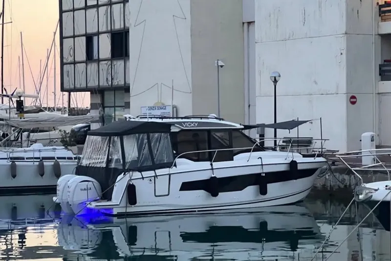  Yacht Photos Pics 2024 Jeanneau Merry Fisher 895 docked at marina, illuminated by blue underwater lights.