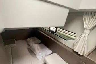  Yacht Photos Pics 2024 Jeanneau Merry Fisher 895 cabin interior with bed, window, and curtains.