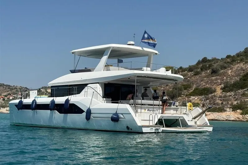  Yacht Photos Pics 2023 Leopard 53 Powercat yacht on serene blue water near rocky coastline.