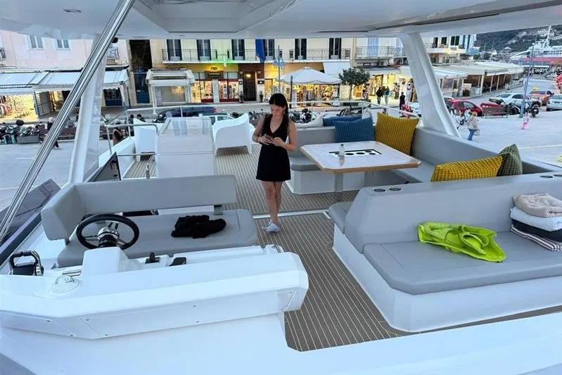  Yacht Photos Pics 2023 Leopard 53 Powercat yacht interior with seating and table, docked at a lively marina.