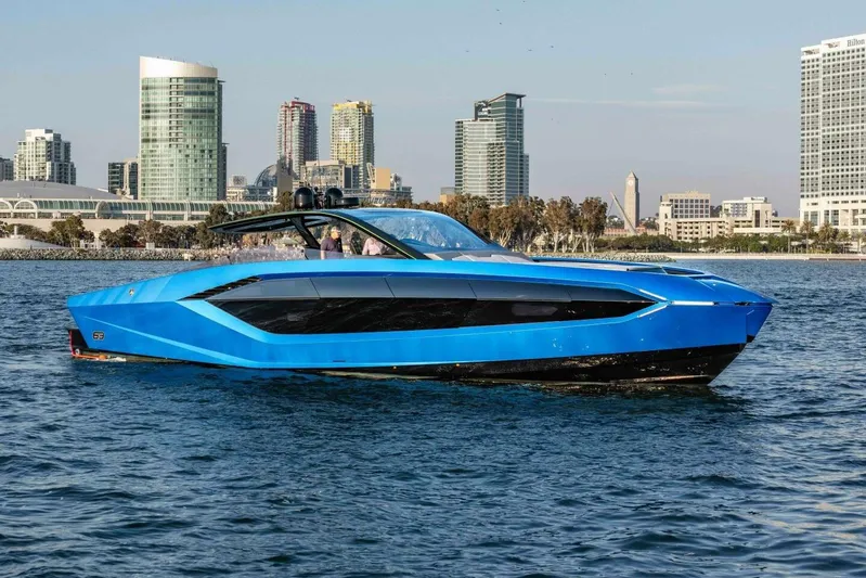 Aspen And Delilah Yacht Photos Pics 2023 Tecnomar 63 Lamborghini yacht in vibrant blue, cruising near a city skyline.