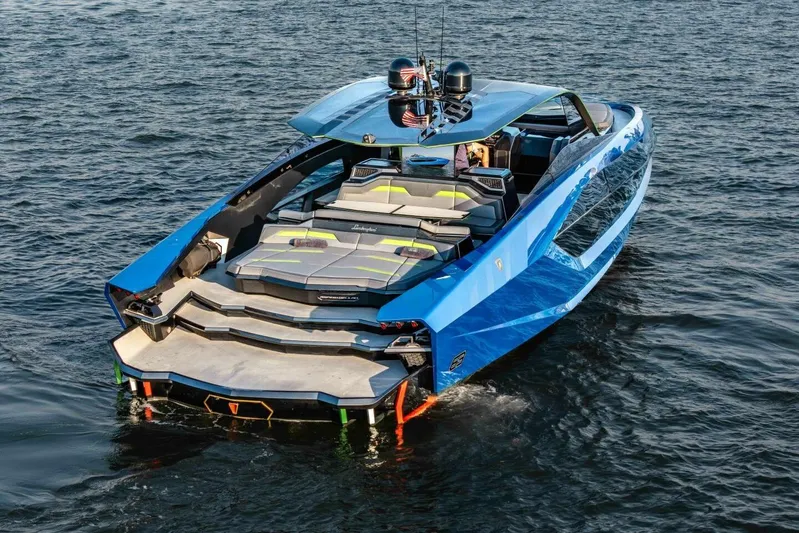 Aspen And Delilah Yacht Photos Pics Luxury 2023 Tecnomar 63 Lamborghini yacht on water, showcasing sleek design and vibrant blue color.