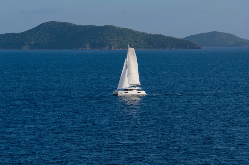 Nauti Mollie Yacht Photos Pics 2020 Fountaine Pajot Astrea 42 Catamaran sailing on blue ocean with scenic island backdrop.