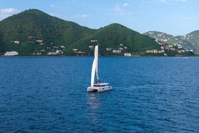 Nauti Mollie Yacht Photos Pics 2020 Fountaine Pajot Astrea 42 Catamaran sailing near lush green hills.
