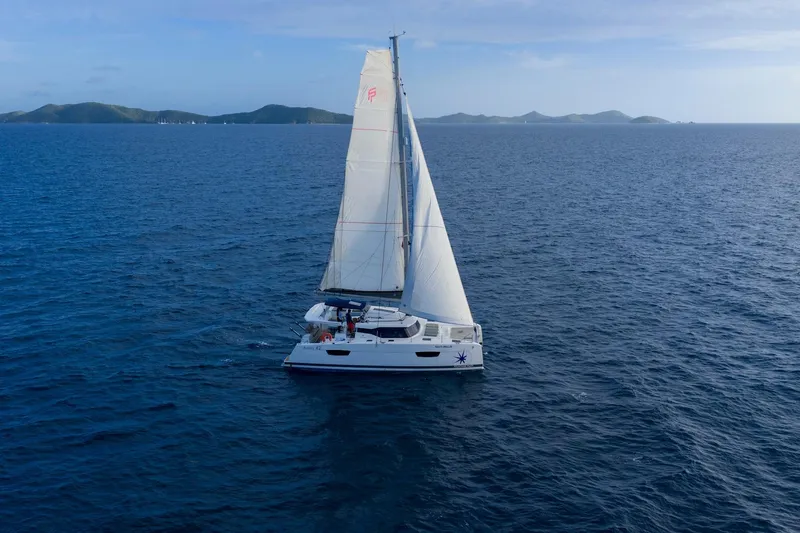 Nauti Mollie Yacht Photos Pics 2020 Fountaine Pajot Astrea 42 Catamaran sailing on open sea with distant islands.