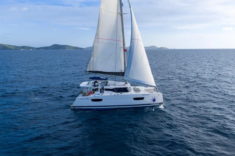 Nauti Mollie Yacht Photos Pics 2020 Fountaine Pajot Astrea 42 Catamaran sailing on open sea with distant islands.