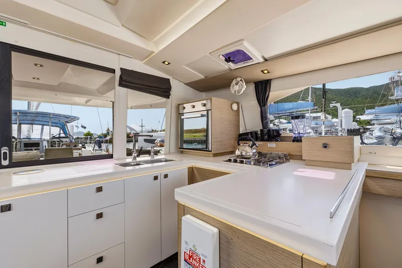 Nauti Mollie Yacht Photos Pics Modern kitchen interior of 2020 Fountaine Pajot Astrea 42 Catamaran with appliances and scenic marina view.