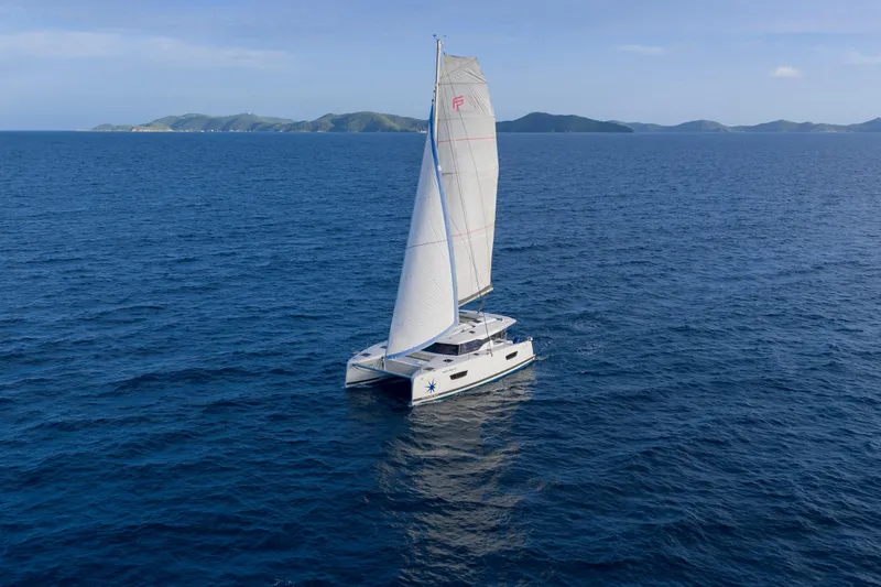 Nauti Mollie Yacht Photos Pics 2020 Fountaine Pajot Astrea 42 Catamaran sailing on open sea with distant islands.