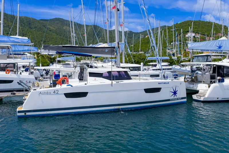 Nauti Mollie Yacht Photos Pics 2020 Fountaine Pajot Astrea 42 Catamaran docked in a marina, surrounded by lush hills.