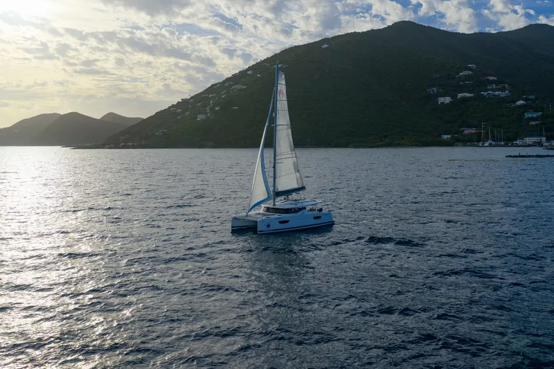 Nauti Mollie Yacht Photos Pics 2020 Fountaine Pajot Astrea 42 Catamaran sailing near lush green hills at sunset.