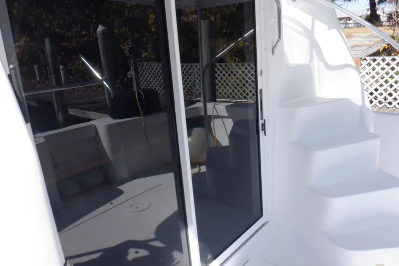 Seaglass Yacht Photos Pics 1999 Mainship 350 Trawler with white exterior, glass door, and steps leading to upper deck.
