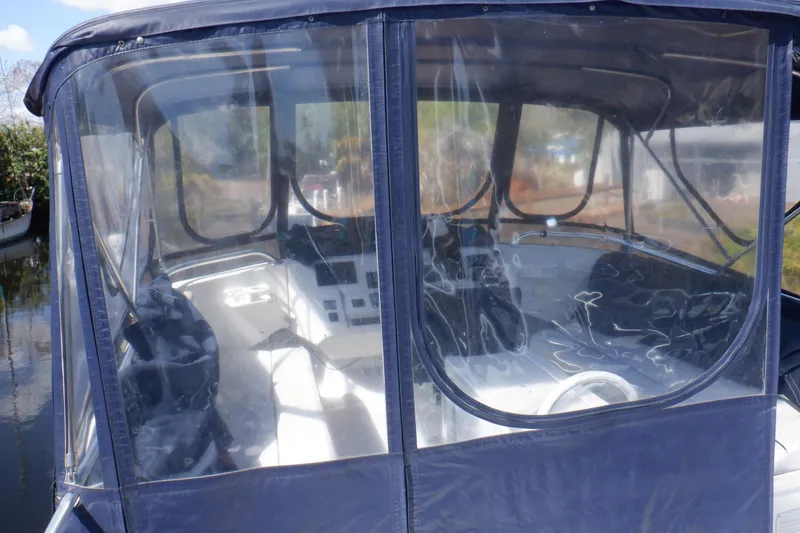 Seaglass Yacht Photos Pics 1999 Mainship 350 Trawler cockpit with clear enclosure and steering wheel visible.