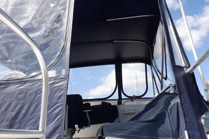 Seaglass Yacht Photos Pics 1999 Mainship 350 Trawler cockpit with blue canopy and clear windows under a blue sky.