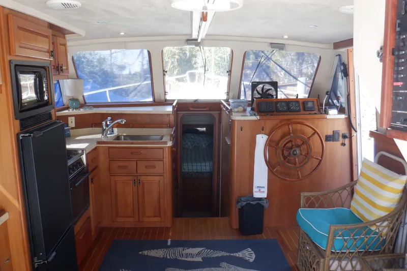 Seaglass Yacht Photos Pics Interior of 1999 Mainship 350 Trawler with kitchen and helm, featuring wooden cabinetry.