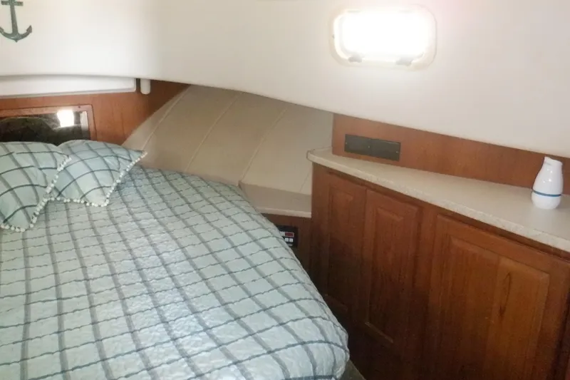 Seaglass Yacht Photos Pics Cozy cabin interior of 1999 Mainship 350 Trawler with bed and wooden cabinetry.