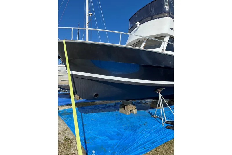 Seaglass Yacht Photos Pics 1999 Mainship 350 Trawler on blue tarp, supported by blocks and stands.