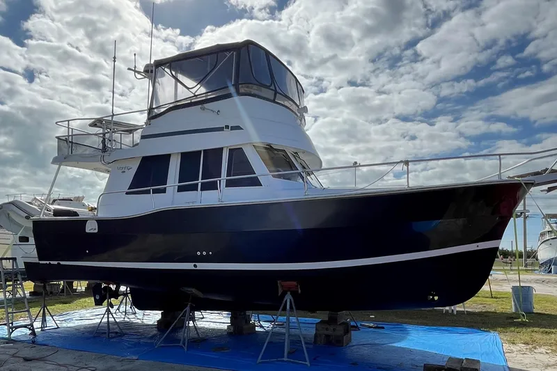 Seaglass Yacht Photos Pics 1999 Mainship 350 Trawler on stands, under cloudy sky, side view.