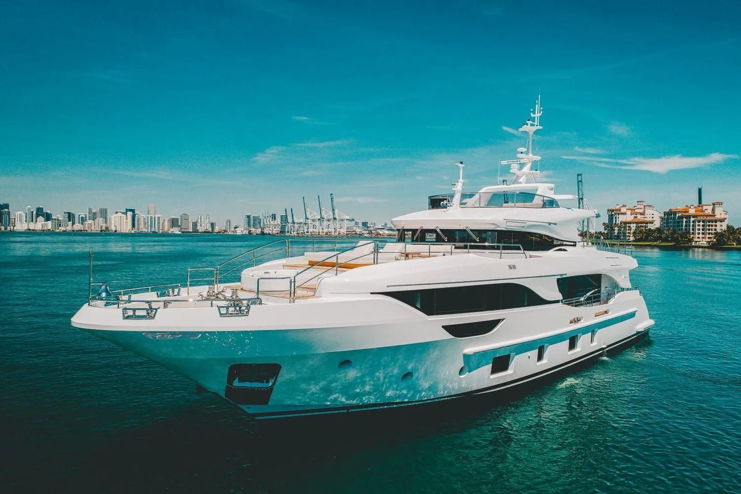 Luxury Benetti Delfino Co Ownership yacht, 2020 model, cruising in a scenic coastal city backdrop.
