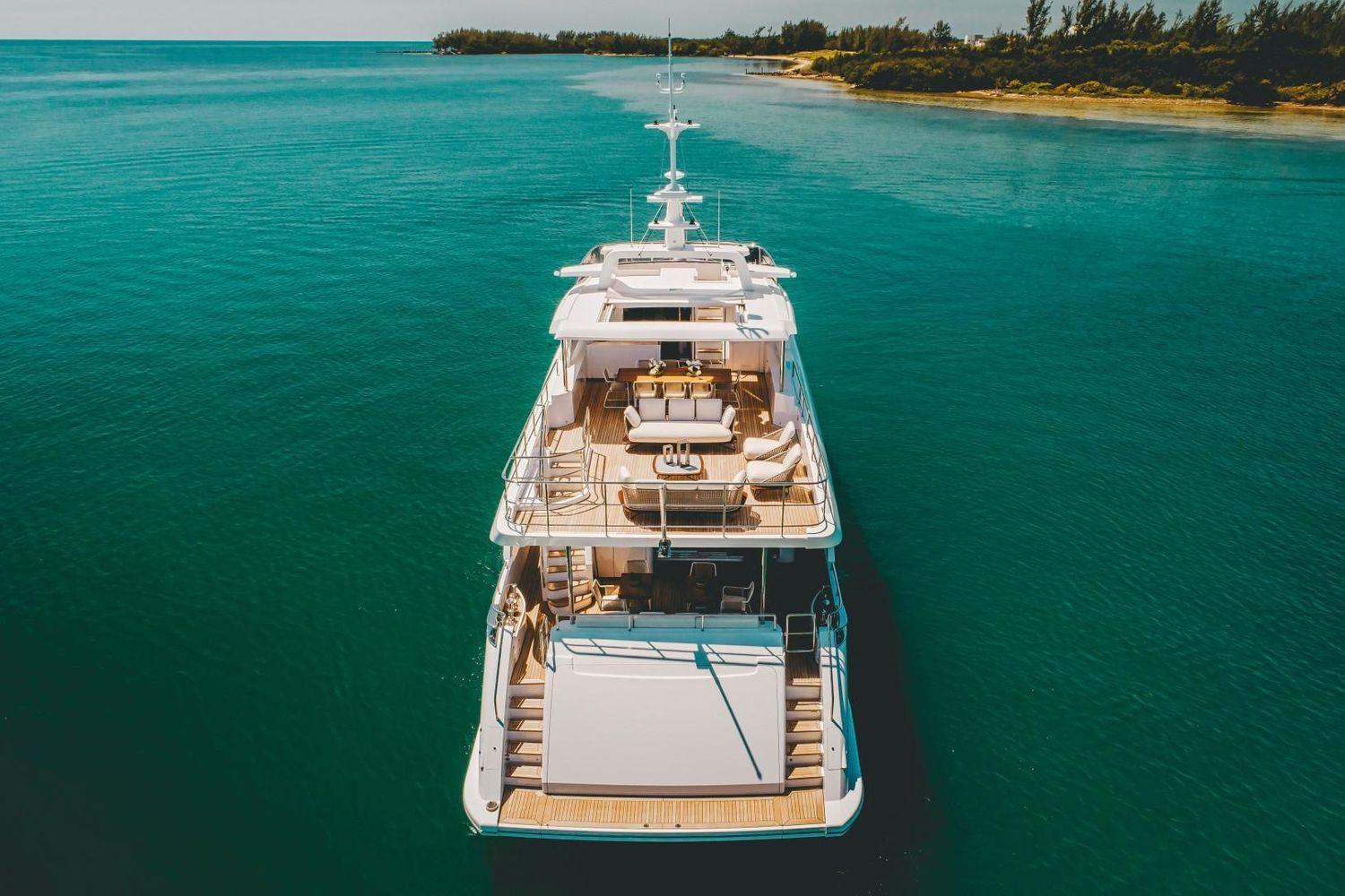 Luxurious 2020 Benetti Delfino yacht on serene turquoise waters near a lush coastline.