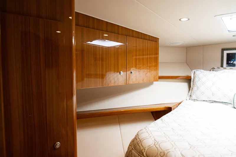  Yacht Photos Pics Luxurious cabin interior of 2021 Viking 44 Open yacht with wood cabinetry and cozy bedding.