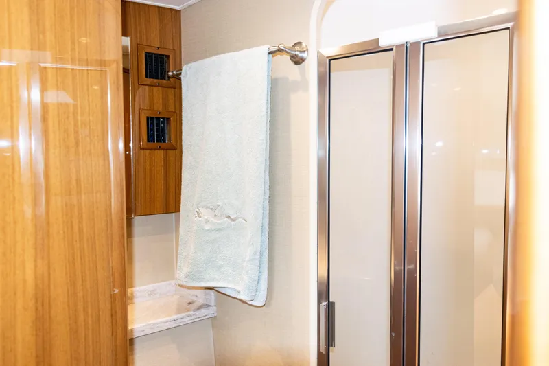  Yacht Photos Pics 2021 Viking 44 Open yacht bathroom with wooden cabinetry and glass shower doors.