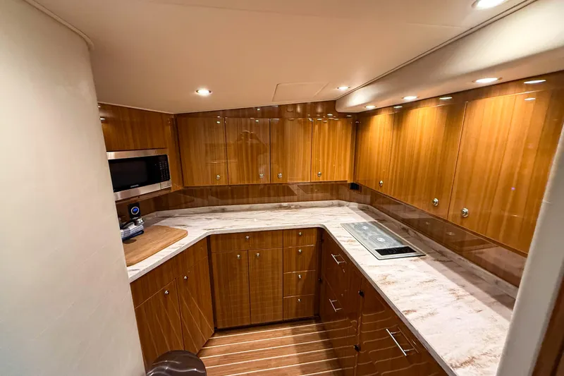  Yacht Photos Pics Luxurious kitchen interior of 2021 Viking 44 Open yacht with wood cabinetry and modern appliances.