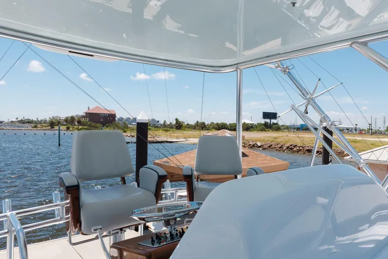 Reely Yacht Photos Pics Flybridge view of 2018 Hatteras GT45X yacht with helm chairs and water backdrop.