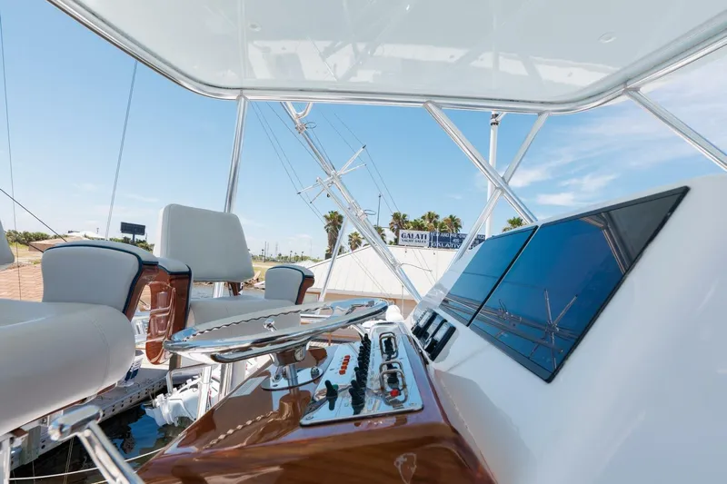 Reely Yacht Photos Pics 2018 Hatteras GT45X Flybridge helm with modern controls and seating, under clear blue sky.