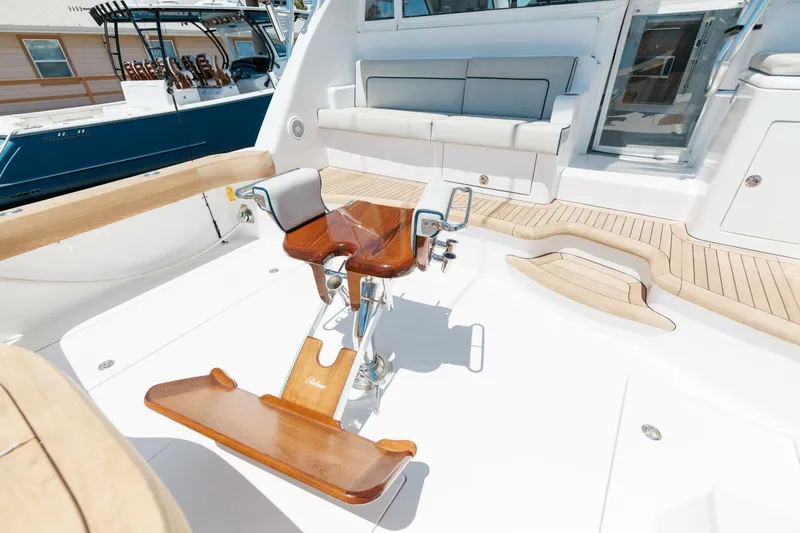 Reely Yacht Photos Pics 2018 Hatteras GT45X Flybridge cockpit with wooden fighting chair and cushioned seating.