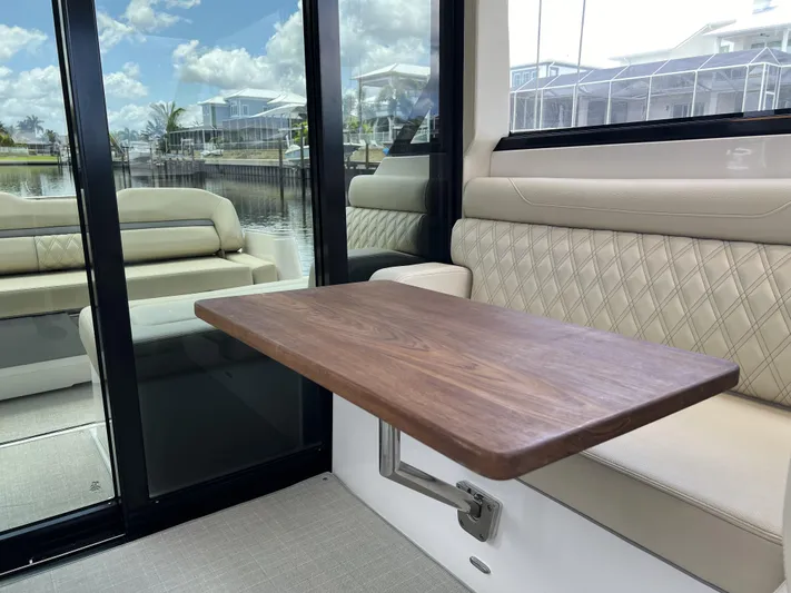  Yacht Photos Pics Interior of 2022 Regal 36 XO yacht with wooden table and cushioned seating.