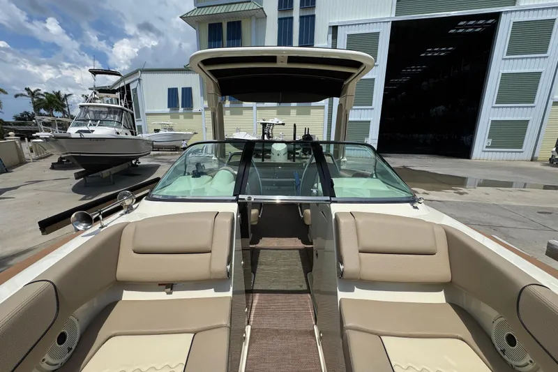 Yacht Photos Pics 2023 Chris-Craft Launch 25 GT boat interior with beige seating, docked near a marina.