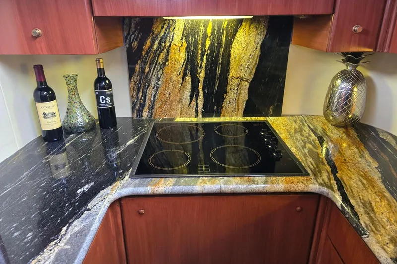  Yacht Photos Pics Luxurious kitchen countertop with wine bottles, glass vase, and modern cooktop on Viking Princess 56 yacht.