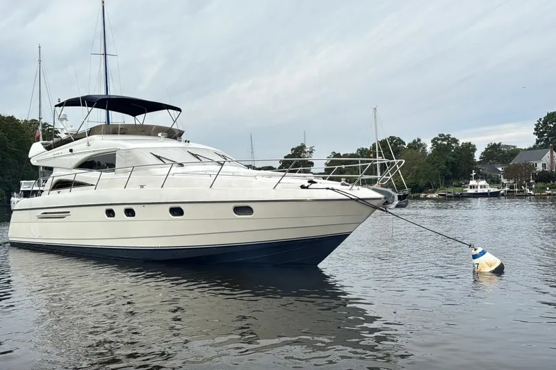  Yacht Photos Pics Luxury 1999 Viking Princess 56 yacht moored on calm waters, surrounded by trees and houses.